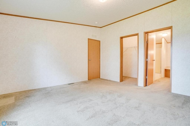 unfurnished bedroom with visible vents, a spacious closet, crown molding, carpet flooring, and a closet