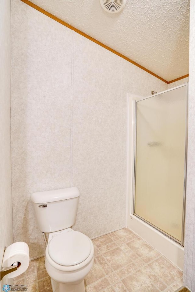 bathroom featuring toilet, a shower stall, visible vents, and a textured ceiling