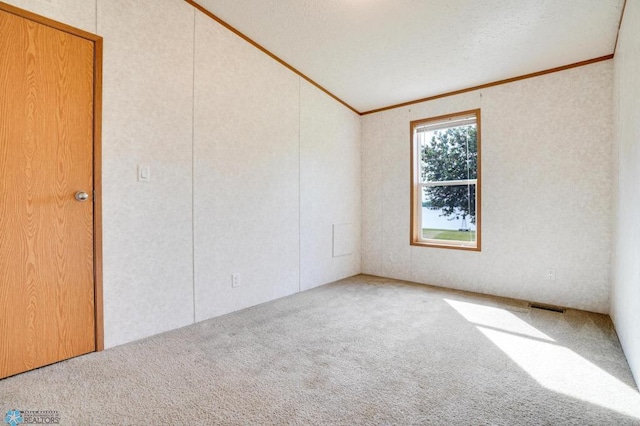 carpeted empty room with a textured ceiling, visible vents, and crown molding