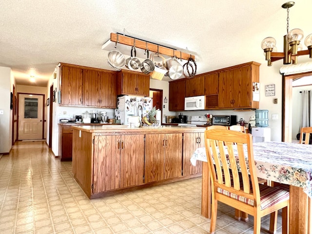 kitchen featuring a notable chandelier, light floors, brown cabinetry, a sink, and white appliances