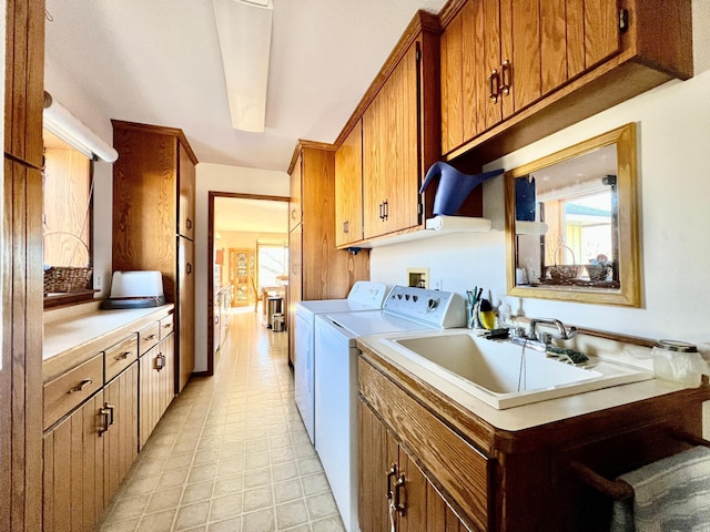 laundry area with a sink, washing machine and dryer, and cabinet space