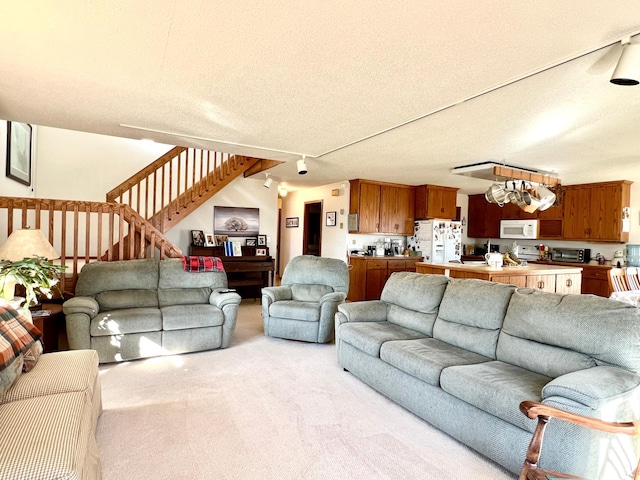 carpeted living room with track lighting, stairway, and a textured ceiling