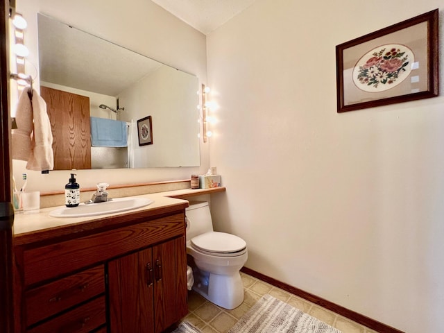 full bath featuring toilet, baseboards, a shower, and vanity