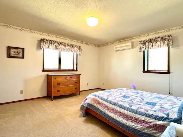 bedroom with multiple windows, light colored carpet, a textured ceiling, and a wall mounted air conditioner