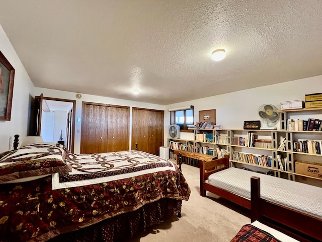 carpeted bedroom with a textured ceiling and multiple closets