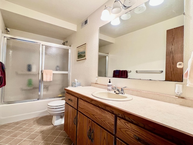 full bathroom featuring shower / bath combination with glass door, visible vents, toilet, vanity, and tile patterned floors