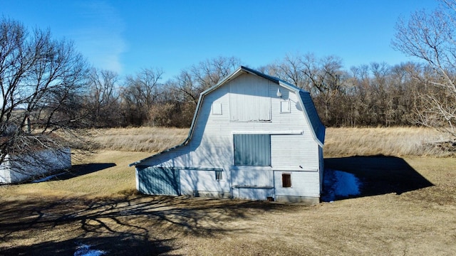 view of property exterior with an outdoor structure, a barn, and a gambrel roof