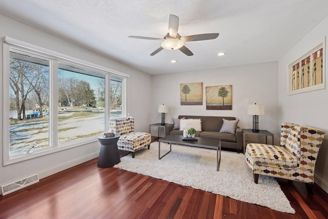 living room featuring a ceiling fan, baseboards, visible vents, recessed lighting, and dark wood-type flooring