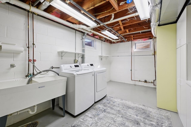 washroom featuring laundry area, washing machine and dryer, and a sink