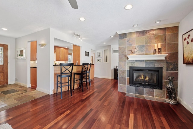 living area with a tiled fireplace, recessed lighting, baseboards, and wood finished floors