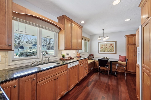 kitchen with a sink, paneled dishwasher, dark wood-style floors, breakfast area, and decorative backsplash