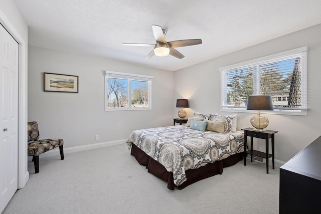 carpeted bedroom with a closet, ceiling fan, a textured ceiling, and baseboards