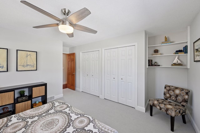 bedroom with visible vents, baseboards, carpet floors, ceiling fan, and two closets