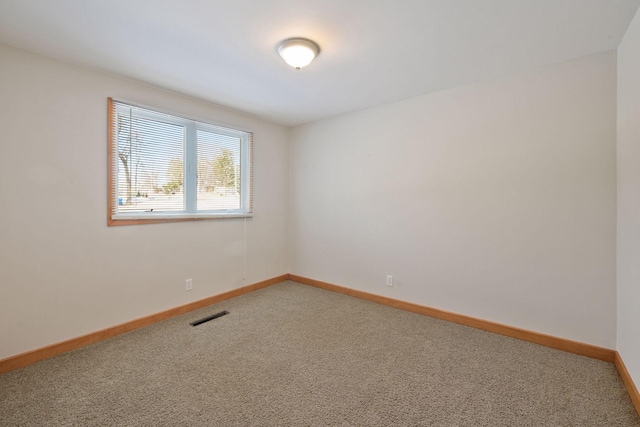 spare room featuring carpet flooring, baseboards, and visible vents