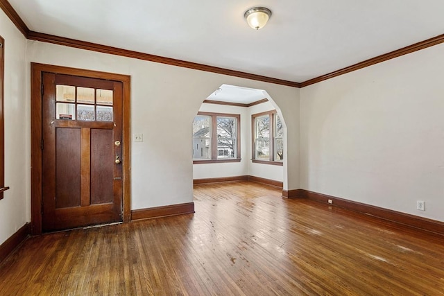 foyer with baseboards, arched walkways, ornamental molding, and hardwood / wood-style flooring