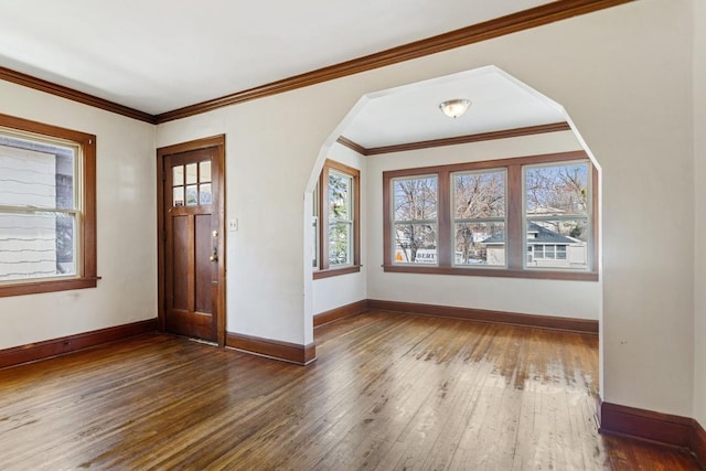 foyer entrance featuring baseboards, arched walkways, wood-type flooring, and ornamental molding