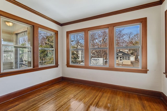 unfurnished room featuring baseboards, wood-type flooring, and ornamental molding