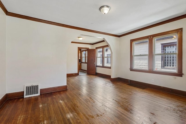 unfurnished room featuring visible vents, arched walkways, baseboards, and hardwood / wood-style flooring