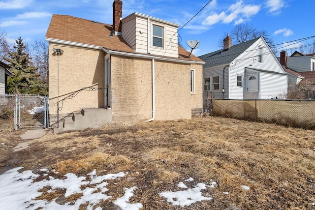 back of house with a gate, fence, and a chimney