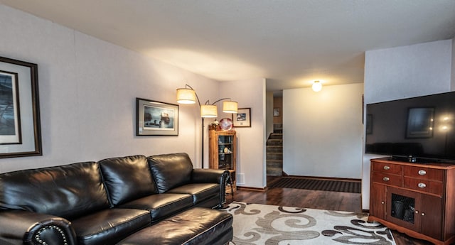 living area featuring dark wood-type flooring, stairway, and baseboards