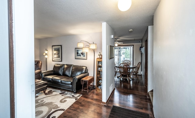 living area with a textured ceiling, baseboards, and wood finished floors