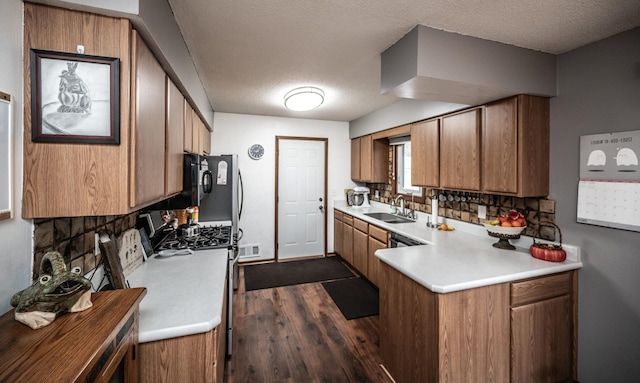 kitchen featuring light countertops, decorative backsplash, brown cabinetry, a sink, and a peninsula