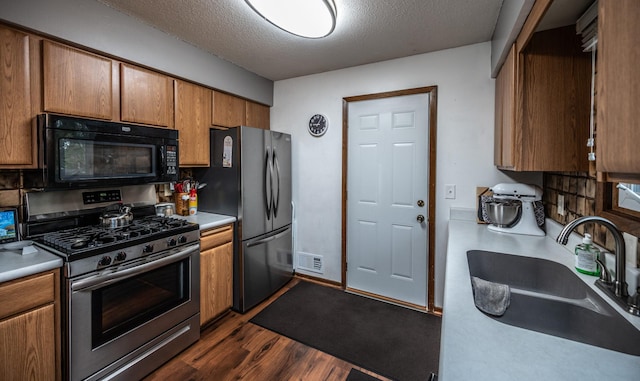 kitchen featuring visible vents, dark wood finished floors, stainless steel appliances, a textured ceiling, and a sink