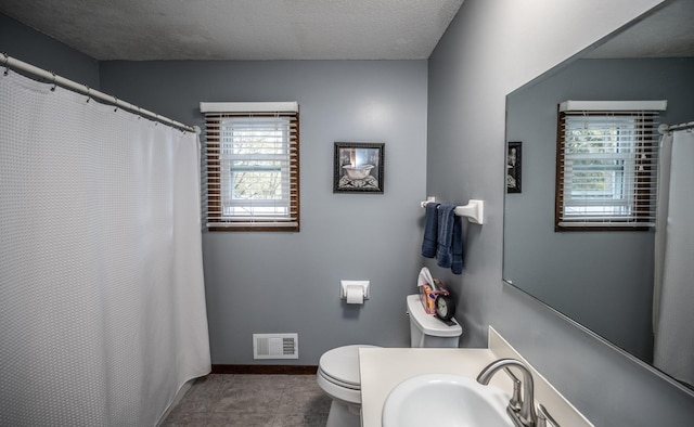 bathroom featuring tile patterned flooring, toilet, a sink, visible vents, and baseboards