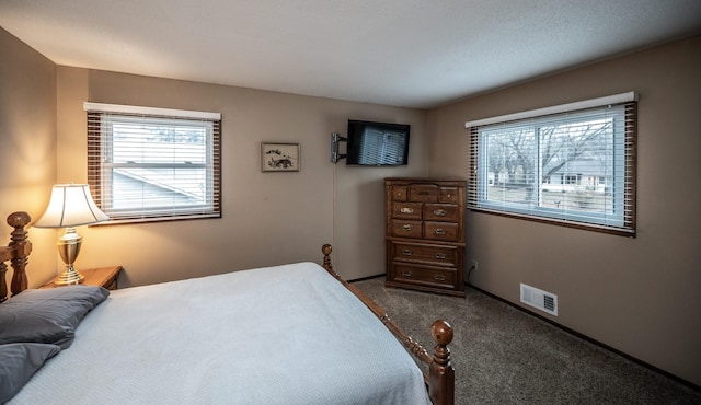 carpeted bedroom with visible vents and multiple windows