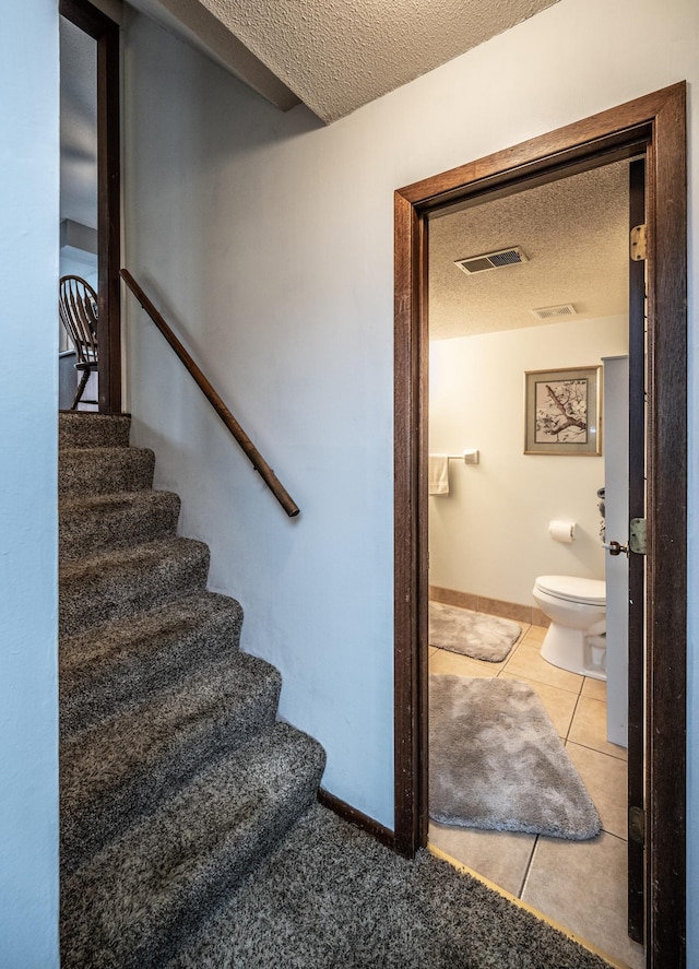 stairs with visible vents, a textured ceiling, and tile patterned floors