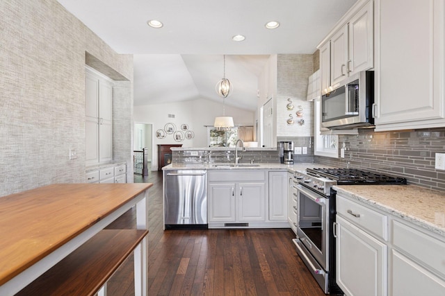 kitchen featuring a peninsula, dark wood-style flooring, a sink, stainless steel appliances, and white cabinets