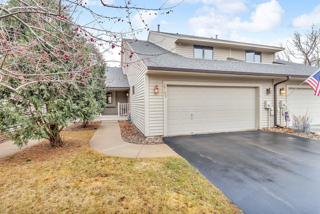 view of front facade featuring driveway, a shingled roof, and an attached garage