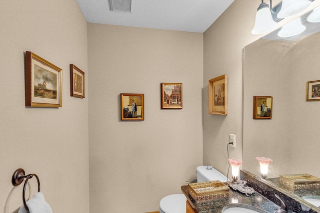 bathroom with toilet, vanity, and visible vents