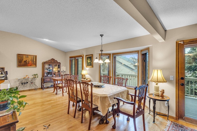 dining space with baseboards, lofted ceiling with beams, a textured ceiling, light wood-style floors, and a notable chandelier