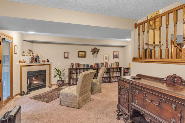 living room with a textured ceiling, carpet floors, a barn door, and a tiled fireplace