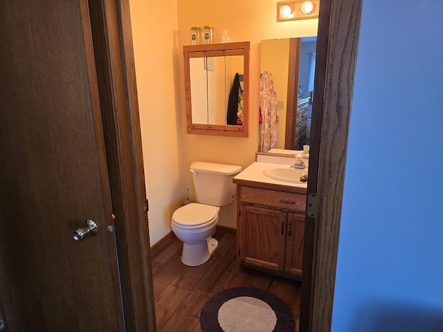 half bathroom featuring toilet, baseboards, wood finished floors, and vanity