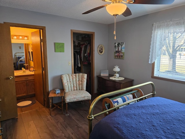 bedroom with ceiling fan, a textured ceiling, hardwood / wood-style flooring, a sink, and a closet