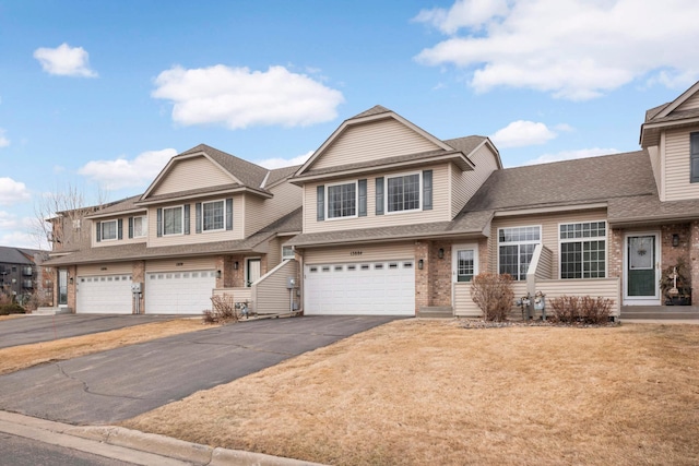 view of front of property with an attached garage, roof with shingles, aphalt driveway, and brick siding