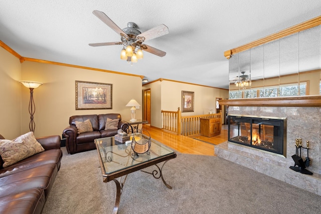 carpeted living room featuring ceiling fan, a textured ceiling, ornamental molding, and a tile fireplace