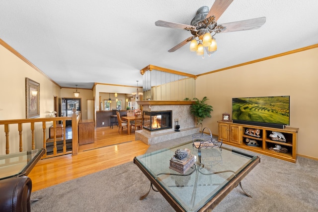 living room featuring carpet floors, ornamental molding, a fireplace, wood finished floors, and a textured ceiling