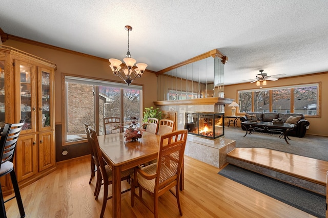 dining area with light wood-style floors, a multi sided fireplace, and ornamental molding