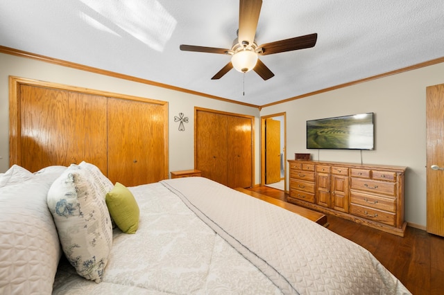 bedroom with a ceiling fan, wood finished floors, a textured ceiling, crown molding, and two closets