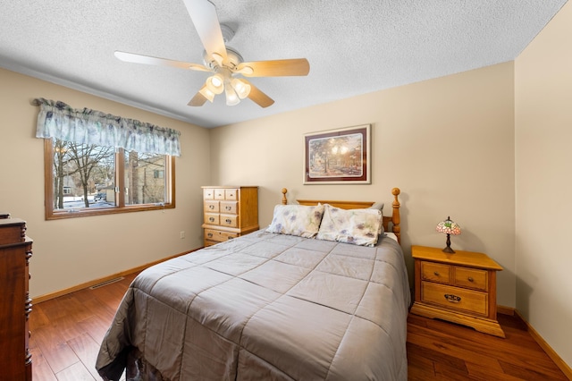 bedroom featuring ceiling fan, a textured ceiling, baseboards, and wood finished floors