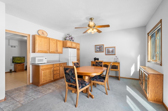 dining space with a ceiling fan, baseboards, and light carpet