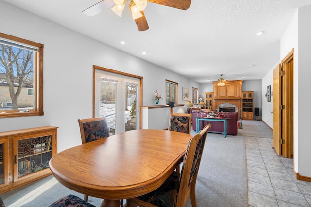 dining room with light tile patterned floors, recessed lighting, ceiling fan, light colored carpet, and a large fireplace