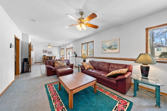 living room featuring ceiling fan, light colored carpet, baseboards, and a textured ceiling