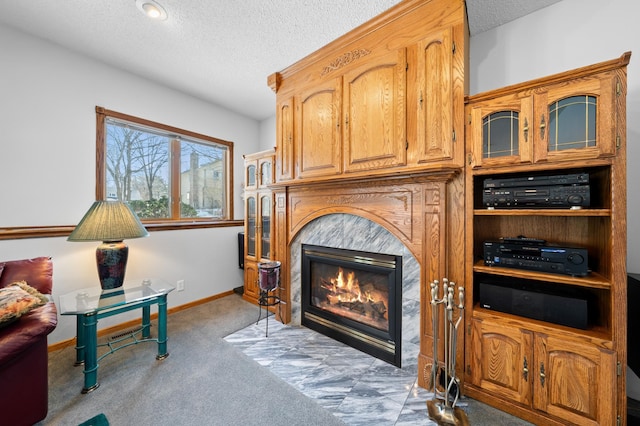 living room featuring baseboards, a fireplace with flush hearth, a textured ceiling, and carpet flooring