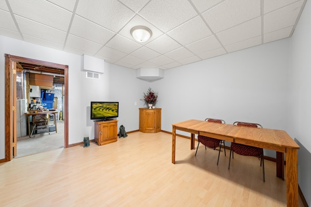 office area with a drop ceiling, light wood-style flooring, baseboards, and visible vents