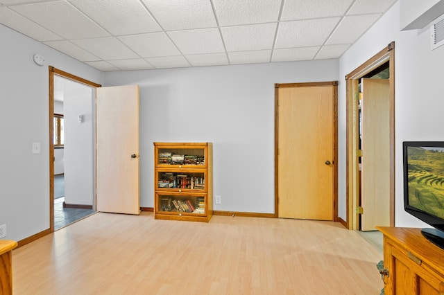 spare room with baseboards, a paneled ceiling, visible vents, and wood finished floors