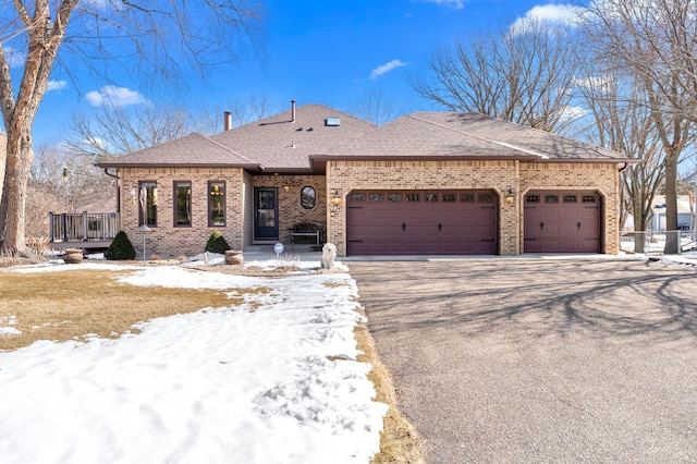 view of front of home featuring driveway, an attached garage, brick siding, and roof with shingles